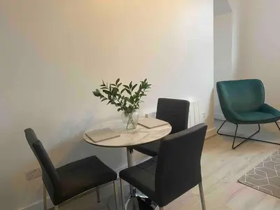 a table with chairs and a vase of flowers on it at Dream Yard Apartments Westcliff in Southend-on-Sea