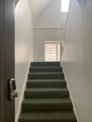 a stairway with green carpeted stairs and a window at Dream Yard Apartments Westcliff in Southend-on-Sea