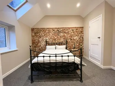 a bed in a room with a brick wall at Spacious Suffolk base in Saxmundham