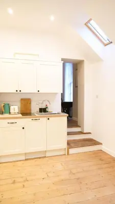 a kitchen with white cabinets and a wooden floor at Spacious Suffolk base in Saxmundham