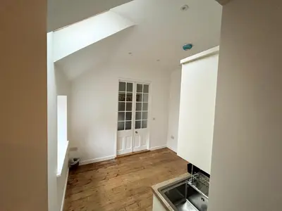 an empty kitchen with white walls and wooden floors at Spacious Suffolk base in Saxmundham