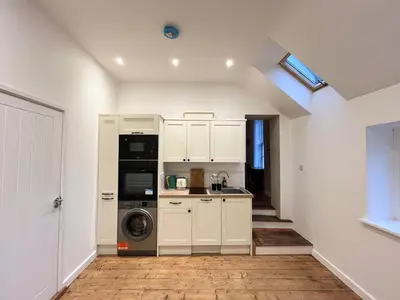 a kitchen with white cabinets and a washer and dryer at Spacious Suffolk base in Saxmundham