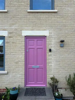 a pink door on the side of a brick building at Meadow Cottage in Trumpington