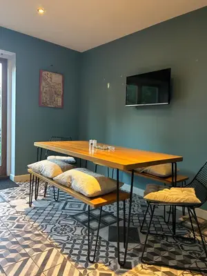 a table and benches in a room with a tv at Meadow Cottage in Trumpington