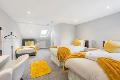 a bedroom with three beds with yellow blankets at Modern Family Home Waltham Abbey Free Parking in Waltham Abbey