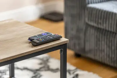 a remote control sitting on top of a coffee table at Modern Family Home Waltham Abbey Free Parking in Waltham Abbey