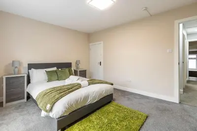 a bedroom with a large bed with a green rug at Modern Family Home Waltham Abbey Free Parking in Waltham Abbey