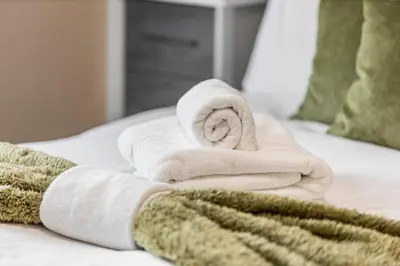 a pile of towels sitting on top of a bed at Modern Family Home Waltham Abbey Free Parking in Waltham Abbey