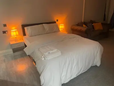 a bedroom with a bed with white sheets and two lamps at Premium studio flat rental in Havering atte Bower