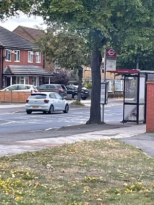 a white car parked at a bus stop on a street at Premium studio flat rental in Havering atte Bower