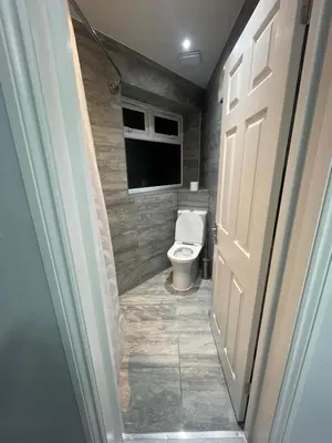 a bathroom with a toilet with a window and a door at Premium studio flat rental in Havering atte Bower