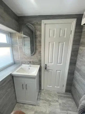 a bathroom with a sink and a mirror and a door at Cozy Studio Flat Romford, London in Romford