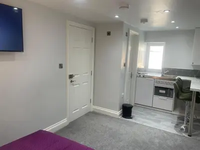 a room with a kitchen with a door and a table at Cozy Studio Flat Romford, London in Romford