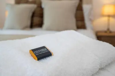 a book sitting on top of a white bed at Victoria Cottage in Monks Eleigh