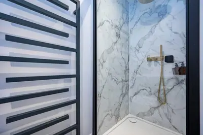 a bathroom with a shower with a marble wall at Victoria Cottage in Monks Eleigh