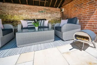 a patio with three chairs and a fire pit at Victoria Cottage in Monks Eleigh