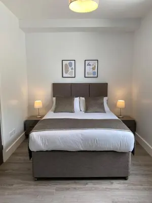 a bedroom with a large bed with two lamps at Dream Yard Apartments in Southend-on-Sea