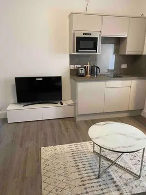 a kitchen with white cabinets and a table and a chair at Dream Yard Apartments in Southend-on-Sea
