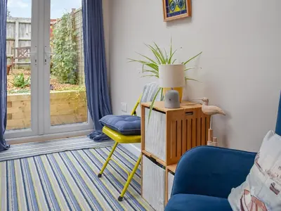a living room with a blue chair and a lamp at Ratcliffe Cottage in Ipswich