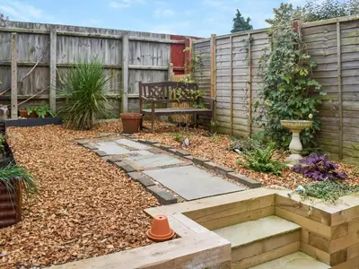 a garden with a bench and a wooden fence at Ratcliffe Cottage in Ipswich