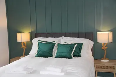 a bedroom with a bed with green pillows and two lamps at East Street Haven - Modern Apartment in Colchester in Colchester
