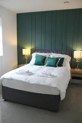 a bedroom with a large bed with green walls at East Street Haven - Modern Apartment in Colchester in Colchester