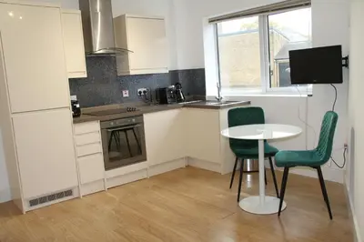 a kitchen with a small table and two green chairs at East Street Haven - Modern Apartment in Colchester in Colchester