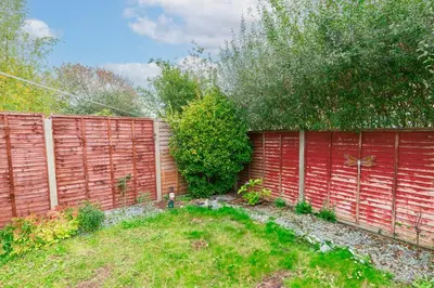 a fence with a red wall and a yard at Comfortable 4-Bedroom Heaven in Thetford in Thetford