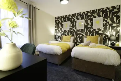 a bedroom with two beds and a black and white wall at Stylish & Cosy Stay 2-Bed House Train Station Hospital Garden Fast WiFi in Colchester
