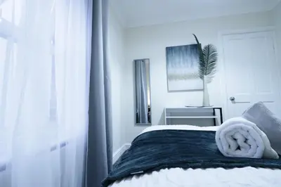 a white bedroom with a bed with a window at Stylish & Cosy Stay 2-Bed House Train Station Hospital Garden Fast WiFi in Colchester