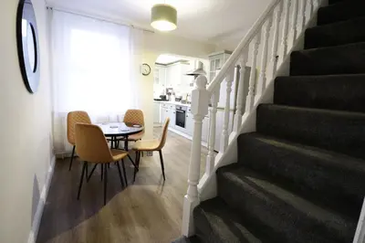 a dining room and kitchen with a table and stairs at Stylish & Cosy Stay 2-Bed House Train Station Hospital Garden Fast WiFi in Colchester