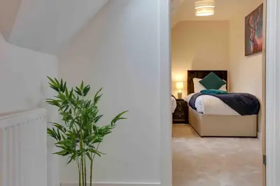 a bedroom with a bed and a potted plant at Kestrel Gardens Five Bedroom Homes in Great Dunmow