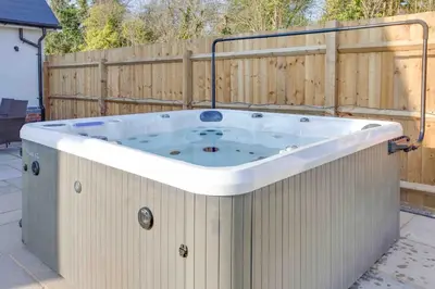 a hot tub in a backyard with a fence at Kestrel Gardens Five Bedroom Homes in Great Dunmow