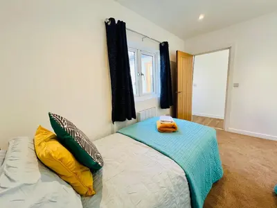 a bedroom with a bed with yellow and green pillows at Stunning 2 bedroom flat for 5 people overlooking the sea 2A in Felixstowe