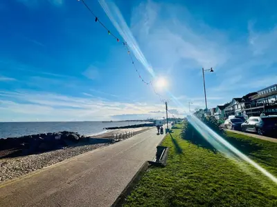 a road next to the ocean with people walking on it at Stunning 2 bedroom flat for 5 people overlooking the sea 2A in Felixstowe