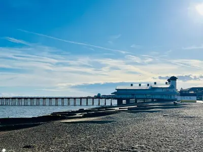 a pier with a building on a beach next to the water at Stunning 2 bedroom flat for 5 people overlooking the sea 2A in Felixstowe