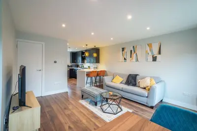 a living room with a couch and a tv and a kitchen at 16 Waterloo Close, Newmarket in Newmarket