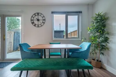a dining room with a table and chairs and a clock at 16 Waterloo Close, Newmarket in Newmarket