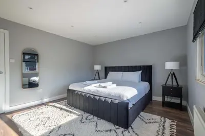 a bedroom with a king sized bed with a rug at 16 Waterloo Close, Newmarket in Newmarket
