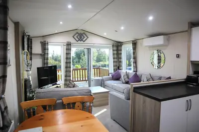 a kitchen and living room with a couch and a table at Amazing Lodge with Hot Tub in Stowmarket