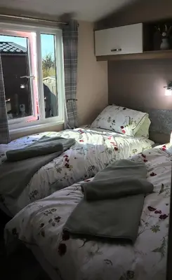 two beds sitting next to a window in a bedroom at Amazing Lodge with Hot Tub in Stowmarket