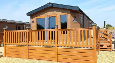a wooden cabin with a gate and a fence at Amazing Lodge with Hot Tub in Stowmarket
