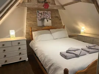 a bedroom with a bed with two towels on it at 15th Century Thatched Cottage in Cambridge