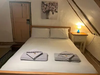 a bedroom with a bed with towels on it at 15th Century Thatched Cottage in Cambridge