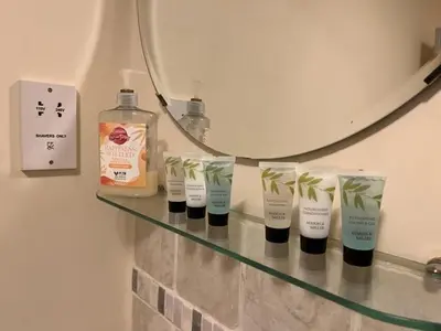 a shelf with four bottles of soap and a mirror at 15th Century Thatched Cottage in Cambridge