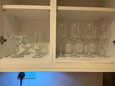 a cabinet filled with wine glasses on a shelf at 15th Century Thatched Cottage in Cambridge