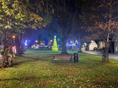 a park at night with a christmas tree and a bench at 15th Century Thatched Cottage in Cambridge