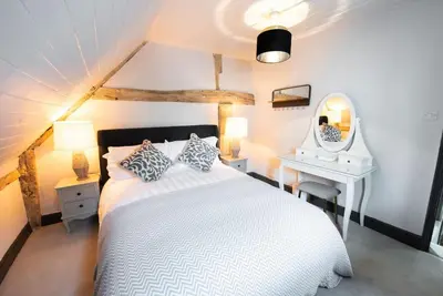 a bedroom with a white bed and a desk and a mirror at Norsey Cottage Billericay in Billericay