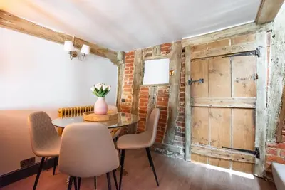 a dining room with a table and chairs and a brick wall at Norsey Cottage Billericay in Billericay