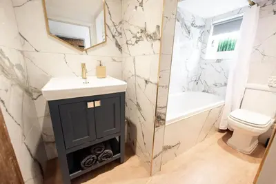 a bathroom with a sink and a toilet and a mirror at Norsey Cottage Billericay in Billericay